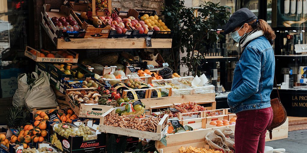 Hyperlocal shopping: A woman looking at groceries at a neighborhood shop.